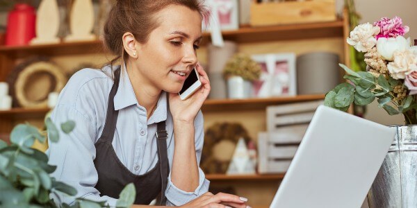 Self-employed woman on the phone while working at laptop